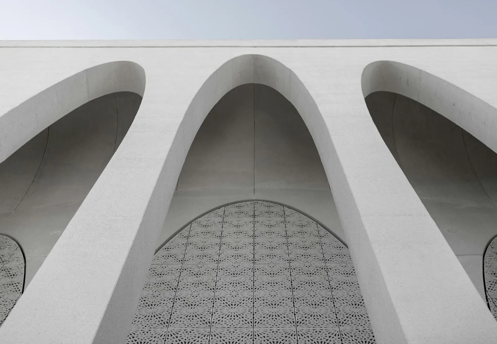 Building a Govern Program With a Team of 5 — Upward view of minimalist architectural arches with a patterned lattice facade,…