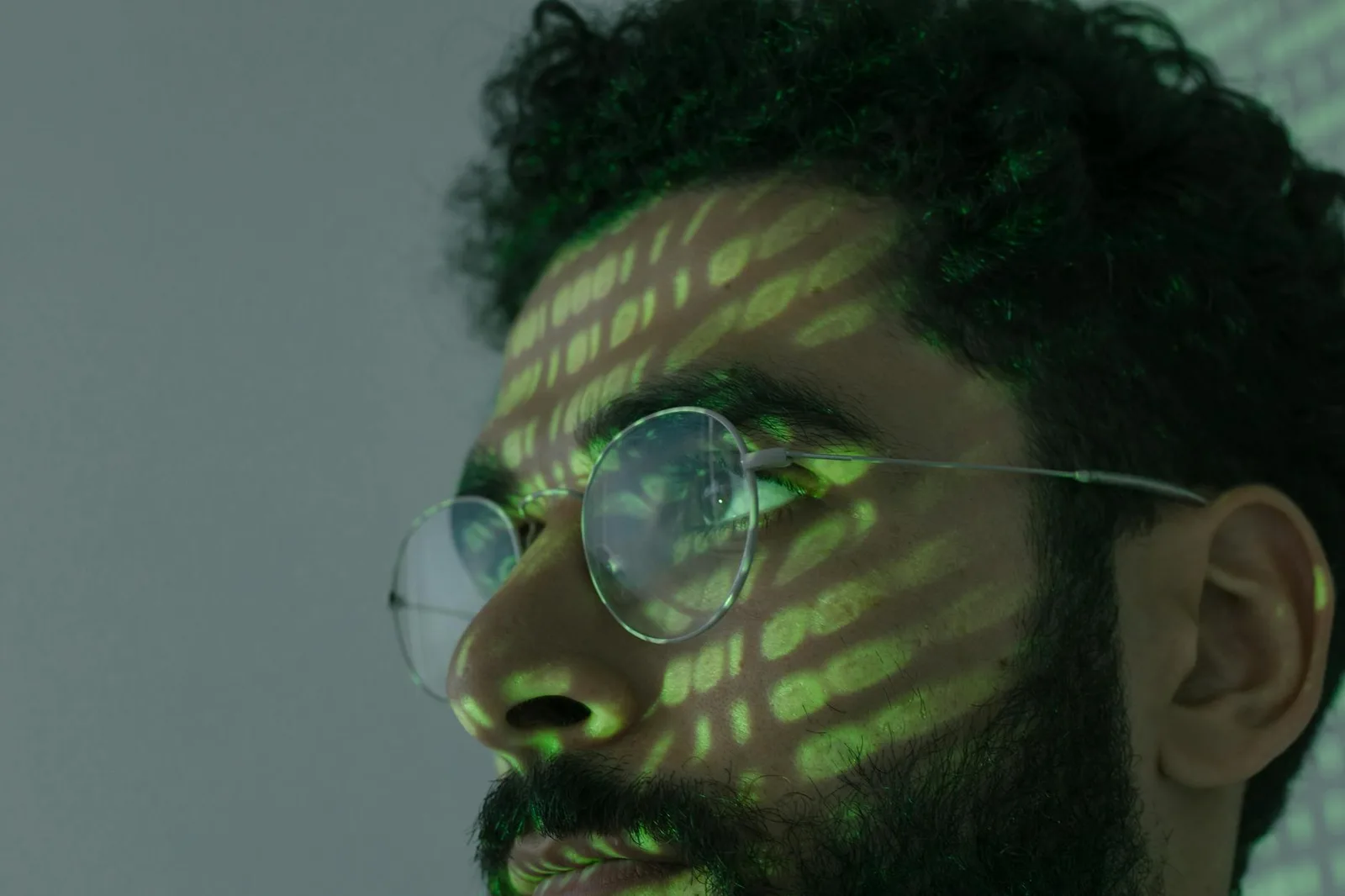 Best Database Security Tools in 2026: Top 7 Compared — A man wearing glasses with binary code projected across his face, symb…
