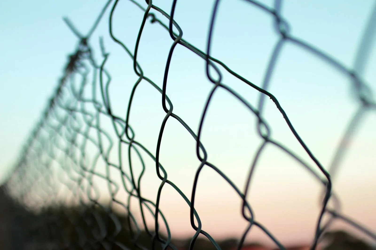 Best Mobile Data Protection Tools in 2026: Top 7 Compared — Detailed view of a chain-link fence against a soft, pastel sky ba…